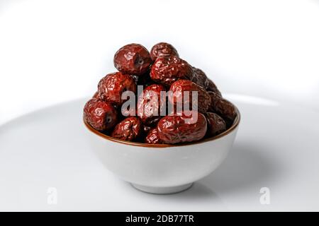 Dried Chinese dates in a ceramic cup on a white background Stock Photo