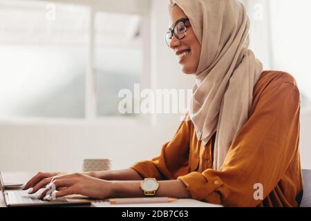 Muslim businesswoman working from home. Woman sitting at home using a laptop. Stock Photo