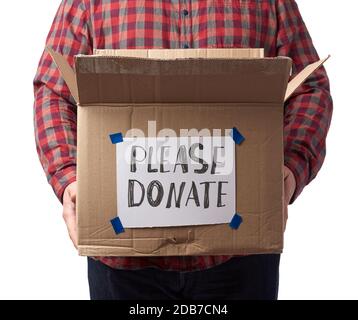 man in a plaid shirt and jeans holds a brown cardboard box with the inscription please donate, concept of a request for help to those in need Stock Photo