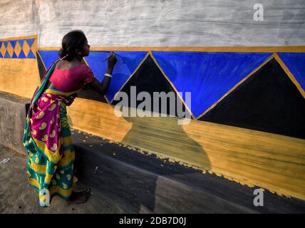 A woman seen decorating a wall of a house with colourful designs during the Bandna Festival celebration.Bandna is a traditional festival of the Kurmi caste tribes and regional people of Purulia & Jharkhand of India where cattle are being worshipped. Stock Photo