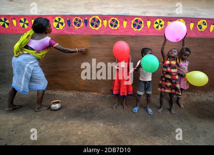 A woman seen decorating a wall of a house with colourful designs during the Bandna Festival celebration.Bandna is a traditional festival of the Kurmi caste tribes and regional people of Purulia & Jharkhand of India where cattle are being worshipped. Stock Photo