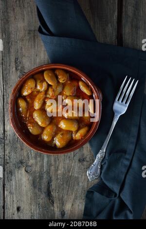 Greek butter beans, known as gigantes, in clay plate on wooden table Stock Photo