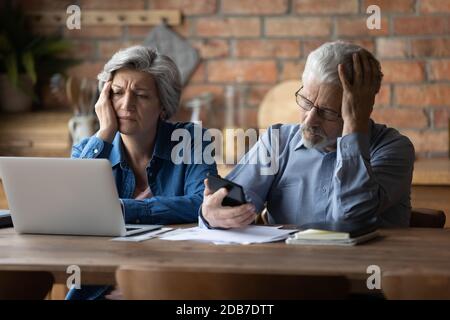 Unhappy mature couple checking financial documents, having problem with money Stock Photo