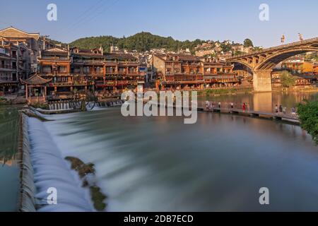 Feng Huang, China -  August 2019 : Long time exposure of the small artificial  cascade waterfall on the Tuo Jiang riverin the Old Town of Fenghuang kn Stock Photo