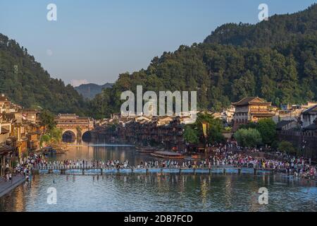 Feng Huang, China -  August 2019 : People crossing Tuo Jiang Tuojiang river, flowing through the centre of Fenghuang Old Town, Hunan Province Stock Photo