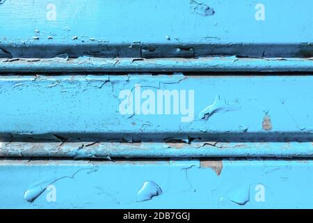 Background of old metal sheet with peel paint texture surface. Painted metal roller shutters door with peeling paint dirty blue hue. Grungy background Stock Photo