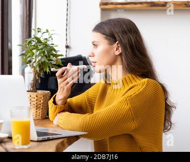 Portrait of positive young woman recording audio message, speaking to microphone Stock Photo