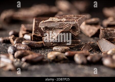 Pieces of chocolate bar. Broken dark chocolate on black table. Stock Photo