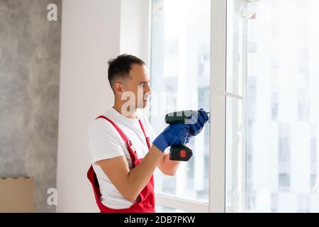 master with a screwdriver sets fittings on the window Stock Photo