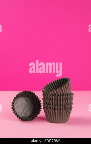 Pinc background with brown paper forms for muffins. Close-up. Stock Photo