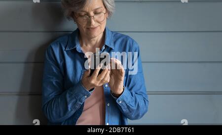 Close up isolated mature woman wearing glasses using smartphone Stock Photo