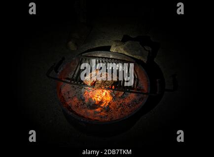 Three ready grilled steaks on a round fire bowl at the bottom Stock Photo