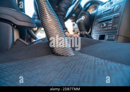 vehicle interior vacuum cleaning. Detail shot of an industrial vacuum cleaner cleaning a car seat. Stock Photo