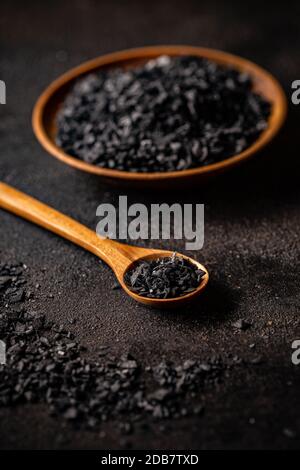 Himalayan black salt in bamboo spoon on black background Stock Photo