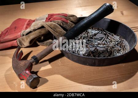 old rusty hammer and construction gloves laid on wooden board in studio Stock Photo