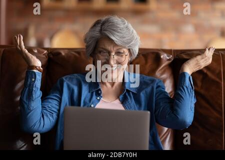 Close up overjoyed mature woman wearing glasses looking at laptop Stock Photo
