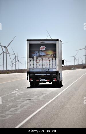 Truck driving on highway past wind mill electricity generators in the high desert of California USA Stock Photo