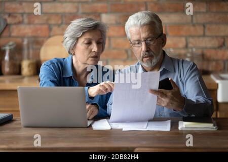 Serious mature couple checking financial documents, planning budget together Stock Photo