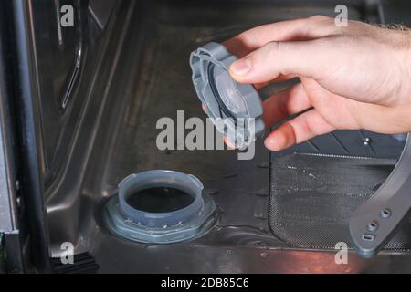 Man opens the container for salt in the dishwasher and fills there a special salt. Stock Photo