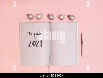 2021 year plans Photo with copy space 2021 year plans Photo with copy space Open notebook with gray pages and silver shiny Christmas baubles on light Stock Photo