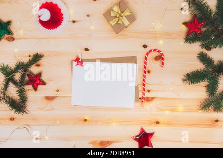 Top view empty paper letter wishlist for Santa Claus with envelope, candy shape pencil, gift box and Christmas decor on a wooden table. Festive mood Stock Photo