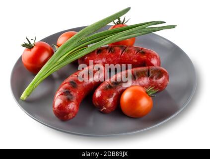 Attractive sausages with tomatoes and onions  on gray plate. Isolated on white background. The concept of traditional food. Stock Photo