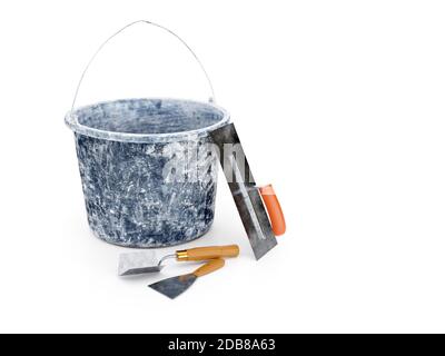 Plasterer's basic tools - dirty plastic bucket, large stainless steel trowel, corner trowel and scraper on white background Stock Photo