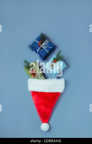 Top view zero waste christmas concept. Packed in natural fabric gifts and decorations from natural materials falling in santa hat. Flat lay. Creative Stock Photo
