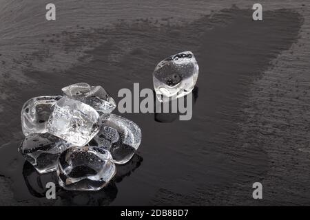 Large ice cubes on black slate board with drops of water Stock Photo