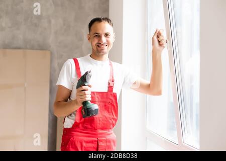 master with a screwdriver sets fittings on the window Stock Photo