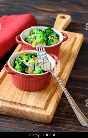Two pots with baked broccoli and cheese on wooden board Stock Photo