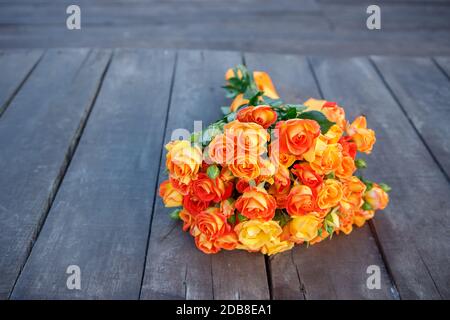 A bouquet of bright orange roses lies on the wooden floor. Copy space Stock Photo