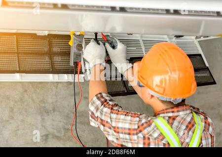 Electrician installing an air conditioning unit on a wall, Thailand Stock Photo