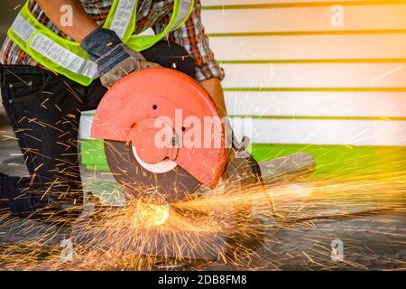 Construction worker using an electric saw on a building site, Thailand Stock Photo