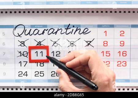 Hand crosses the next quarantine day with a black felt-tip pen Stock Photo