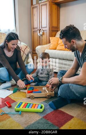 Parents playing with toddler a wooden game building Stock Photo