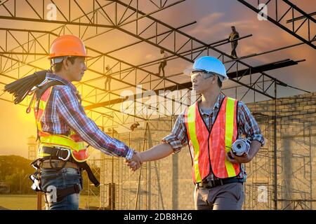 Two engineers shaking hands on a construction site, Thailand Stock Photo