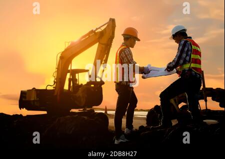 Two engineers looking at building plans on a construction site, Thailand Stock Photo