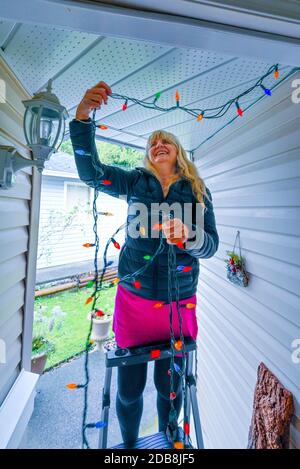 Woman installing Christmas Holiday lights. Stock Photo