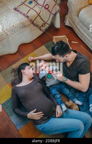Parents playing with their sad little son in the living room Stock Photo