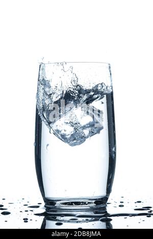 Ice cube falling in a glass of water splash water drops Stock Photo