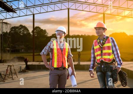 Two engineers looking at building plans on a construction site, Thailand Stock Photo