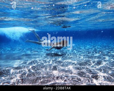Girl swimming underwater in ocean, Maldives