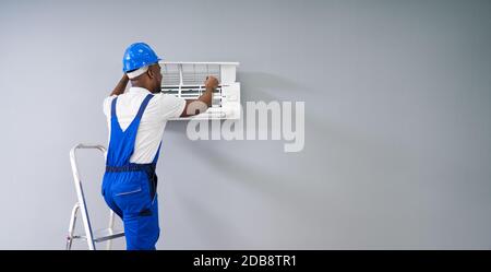 Happy Young African Male Technician Repairing Air Conditioner Stock Photo