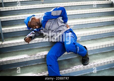 Worker Man Lying On Staircase After Slip And Fall Accident Stock Photo
