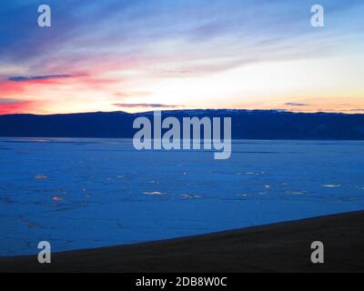 Picturesque sunset on the background of mountains and melting ice on lake Baikal Stock Photo