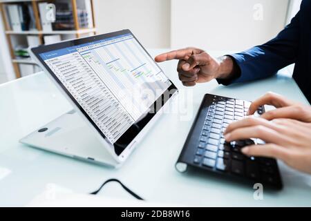 Two Young Businesspeople Analyzing Gantt Chart On Laptop Stock Photo