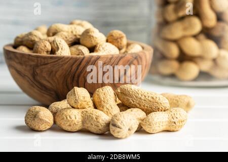 Tasty unpeeled peanuts. Peanuts in nutshell on white table. Stock Photo