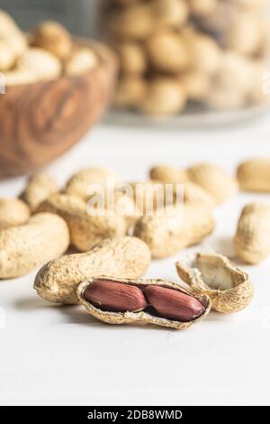 Tasty unpeeled peanuts. Peanuts in nutshell on white table. Stock Photo