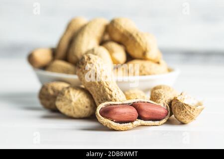 Tasty unpeeled peanuts. Peanuts in nutshell on white table. Stock Photo